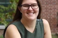 a woman in a green shirt sitting in front of a brick building 