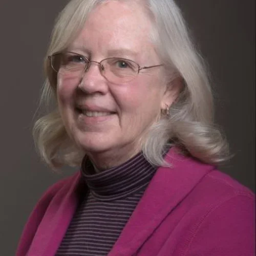 An older lady wearing glasses and a pink coat