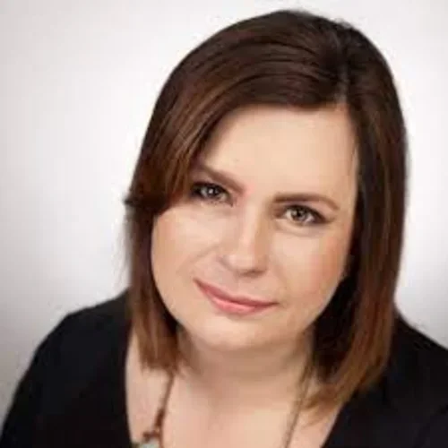 a brunette woman with a necklace and black shirt looking up at the camera