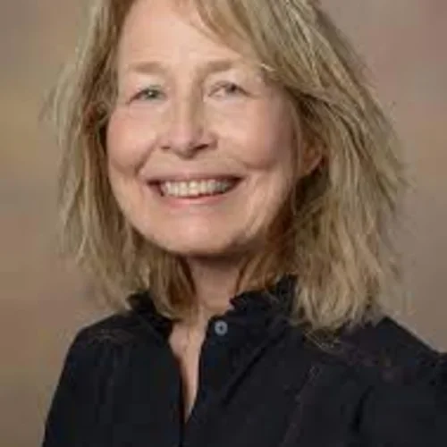 an older woman smiling with blonde hair and a black collared shirt