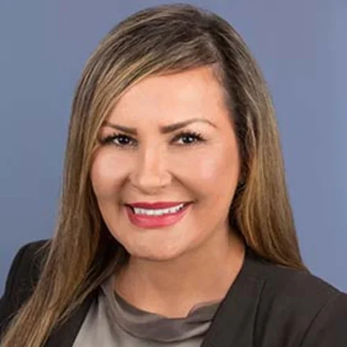 a woman with light brown hair and a black jacket against a light blue background