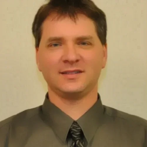 A man wearing a green shirt against a beige background