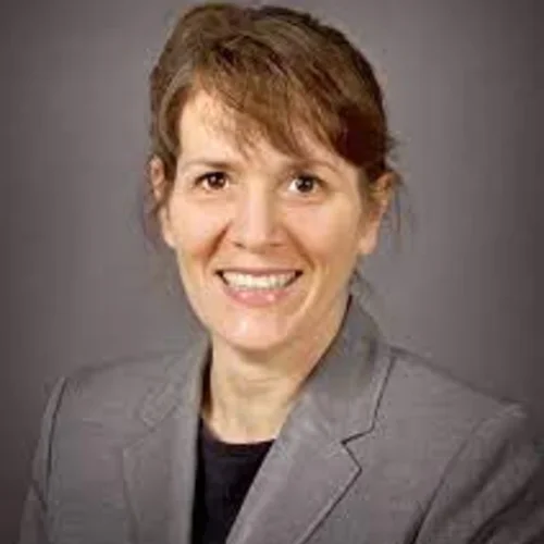 A woman wearing a grey suit jacket against a grey background