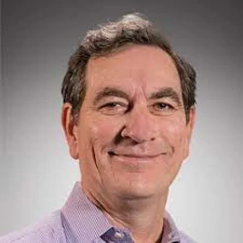A man wearing a light purple shirt against a gradient dark background