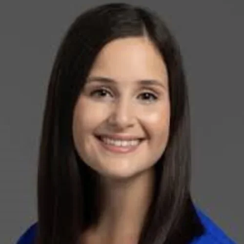 A woman with dark hair, wearing a blue shirt