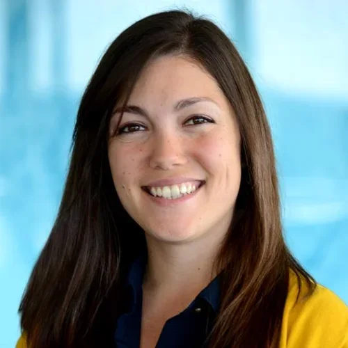 A woman with brown hair, wearing a yellow sweater