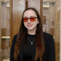 A woman with dark hair, wearing red glasses
