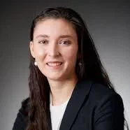 A woman with long dark hair, wearing a black suit jacket