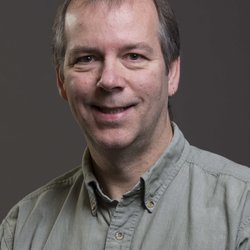 a middle aged man wearing an olive green collared shirt