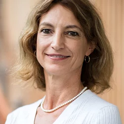 A woman with shoulder length hair, wearing a necklace and a white shirt