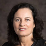 A woman with dark hair against a dark background