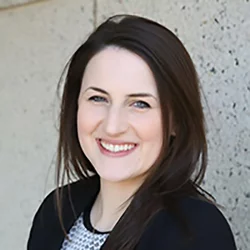 A woman with dark brown hair, wearing a blazer
